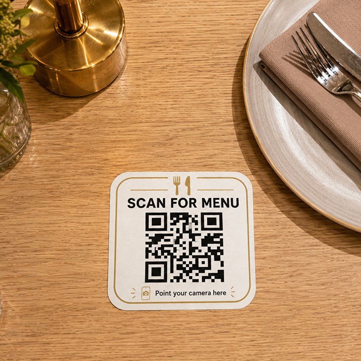 Een gedrukte kartonnen QR-kaart met 'Scan for menu' op een gedekte tafel